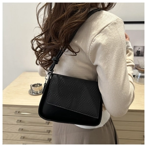Close-up of black leather crossbody bag with woven texture and decorative knot strap