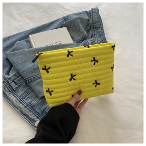 Nahaufnahme der gelben gesteppten Clutch mit schwarzer Schleifenstickerei und Textur