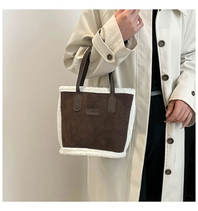 Close-up of brown suede bucket bag with white faux fur trim and fashion leather label