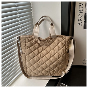 Detail of beige quilted tote bag with diamond pattern and adjustable shoulder strap