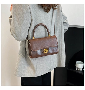 Brown vintage square handbag with gold metallic twist lock shown on a model's shoulder