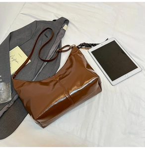 Detailed macro view of the glossy brown leather tote bag with iconic triangle metal logo