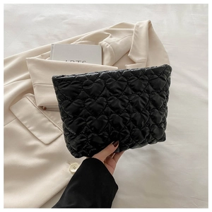 Detail of black quilted heart pattern on portable cosmetic bag held in hand