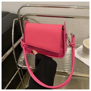 Detail of rose pink handbag with woven texture flap and stylish knot shoulder strap