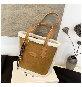 Detail of brown suede bucket bag with white fleece trim and decorative bell pendant
