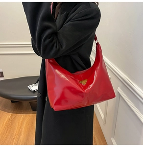 Detail of red glossy hobo bag with triangle metal logo plaque on black winter coat