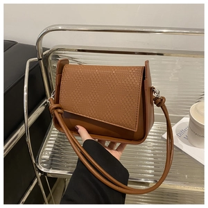 Detail of caramel crossbody bag featuring woven texture flap and knot strap detail