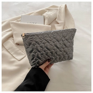 Detail of gray quilted heart pattern cosmetic bag with golden zipper in lifestyle setting