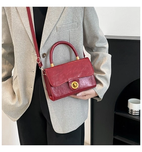 Retro red leather crossbody bag with golden buckle styled on a grey suit jacket