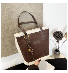 Detail of suede tote bag with faux fur trim, leather handles and decorative bell charm