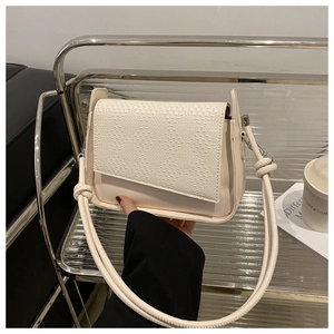 Detailed close-up of woven texture on the cream leather crossbody bag flap