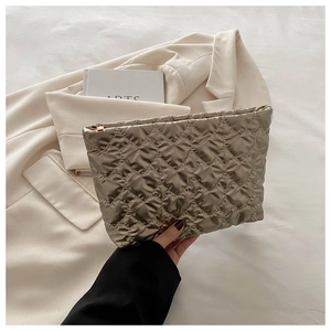 Macro detail of champagne gold quilted heart pattern and metallic zipper on vanity bag