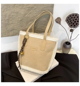 Detail view of suede tote bag with lamb wool trim and decorative bell knot charm