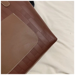 Detailed view of brown checkered embossed leather tote bag with contrast stitching