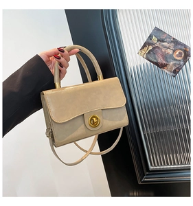 Detail of elegant beige leather handbag with gold twist lock and adjustable shoulder strap