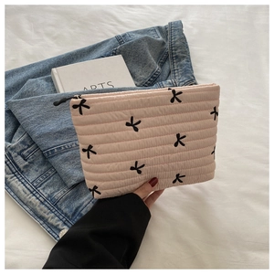 Nahaufnahme einer gesteppten rosa Kosmetiktasche mit schwarzen Schleifen und Baumwolltextur
