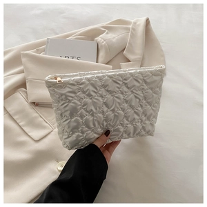 Close-up of quilted heart pattern on a white handheld cosmetic bag with gold zipper
