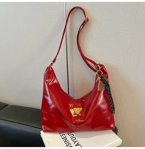 Detail of red glossy leather tote featuring a gold triangle logo and tennis racket charm