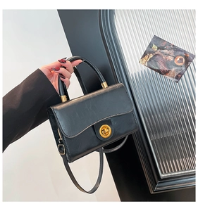 Close-up of retro black crossbody bag showing textured PU leather and gold twist lock