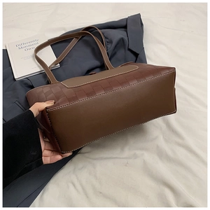 Detail view of brown tote bag showing woven texture side panels and smooth leather base