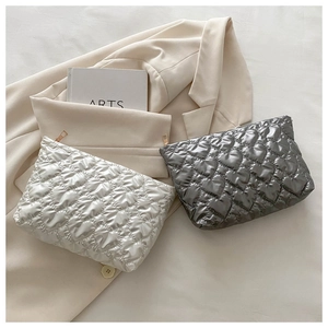Detail of heart-quilted makeup bags in pearl white and metallic grey with gold zippers