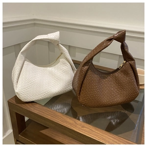 Detailed view of woven hobo bags with knot handles in white and brown faux leather