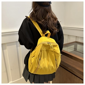 Dettaglio dello zaino in nylon giallo con trama del tessuto e tasche con cerniera simmetrica