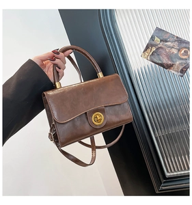 Detail of vintage brown leather bag featuring a gold metal twist lock and handle