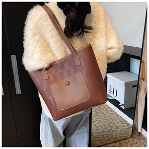 Detail of dark brown tote bag with textured block pattern and functional outer pocket
