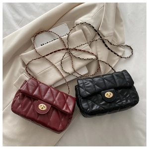 Close-up of quilted chain bags in black and burgundy on a stylish white blazer