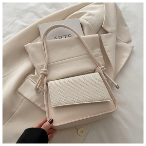 Detailed view of cream woven texture flap and knotted strap on minimalist shoulder bag