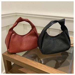 Close-up of woven leather texture and iconic knot handle on red and black shoulder bags