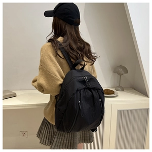 Vista posteriore di uno zaino leggero in nylon nero indossato da una modella in stile casual