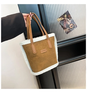 Detail of brown suede tote with white shearling trim and leather fashion patch