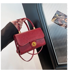 Detail of deep red leather vintage bag with golden rotary clasp and top handle strap
