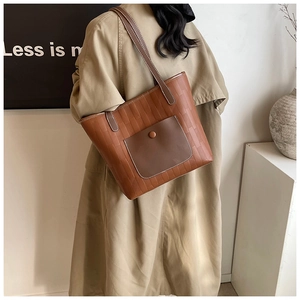 Detail of a brown textured tote bag with contrast pocket on a khaki trench coat model