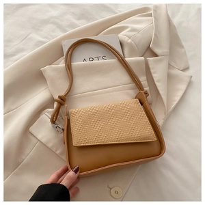Detail of brown leather bag with beige woven texture panel in a lifestyle setting