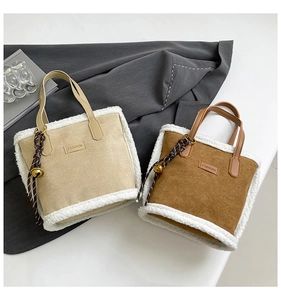 Detail of suede tote bag with faux fur trim, fashion label, and decorative charm