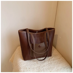 Deep brown tote bag detail with subtle checkered texture and leather front pocket flap