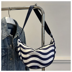 Detail of blue and white wavy pattern on a crescent dumpling bag with a black strap