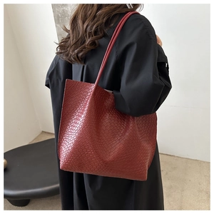 Close-up of deep burgundy woven texture and handle on a retro shoulder tote bag
