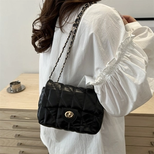Quilted black crossbody bag with gold rotating lock and chain strap on female model