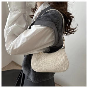 Detailed view of cream faux snakeskin shoulder bag worn with minimalist aesthetic outfit
