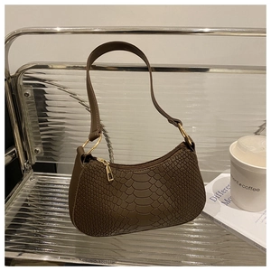 Detail of dark brown snakeskin embossed handbag with golden rings and metal zipper