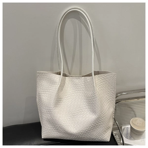 Detailed view of large white woven tote bag with textured PU surface and shoulder strap