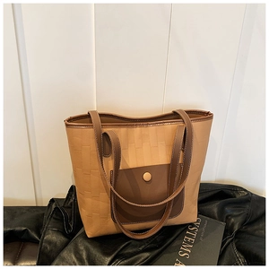 Detail of khaki woven tote bag featuring a brown leather pocket and snap button closure