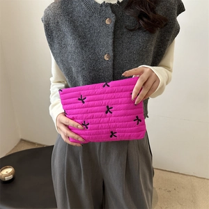 Rosarote gesteppte Clutch mit schwarzen Schleifenstickereien und modernem Design
