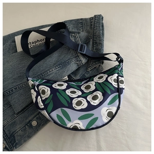Detail of floral printed crescent bag with adjustable strap on denim jacket background