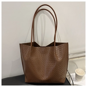 Detail of dark brown woven leather texture on a large capacity tote bag with shoulder straps