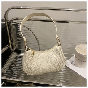 Detail of white snakeskin texture and gold metal rings on a vintage baguette shoulder bag